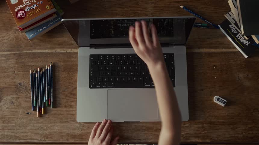 A child opens a laptop and begins typing on the keyboard