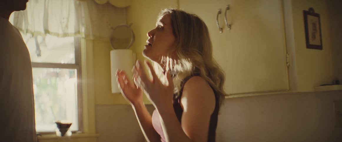 Couple argues in a lit kitchen while the woman holds a plate