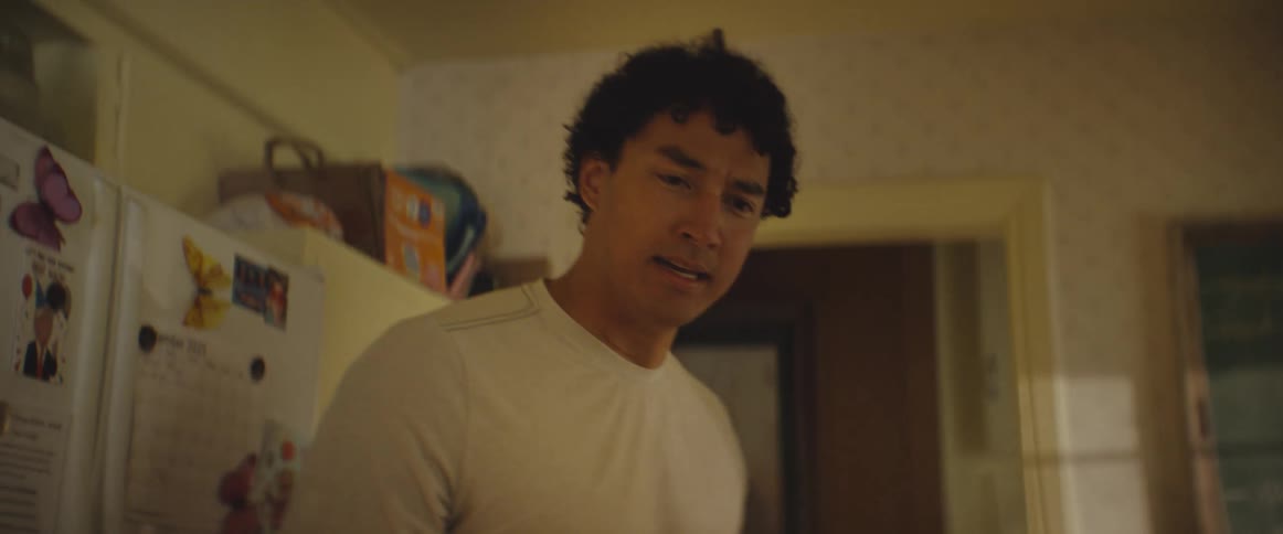 A man with curly dark hair expresses intense anger and frustration while shouting in a kitchen setting he then turns away and walks out of the room through a doorway leaving the space empty as the camera lingers on the kitchen interior