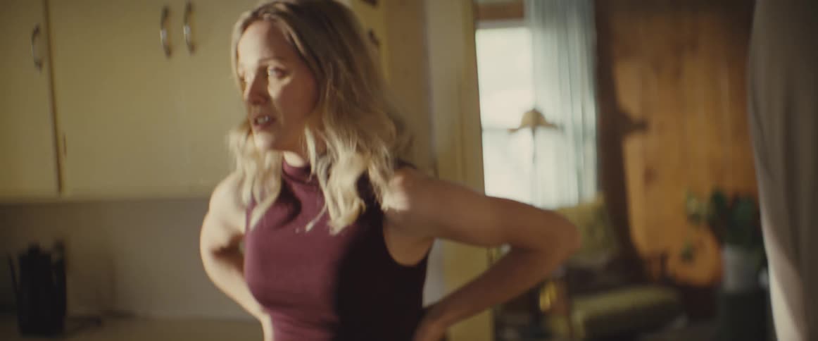 A couple in a heated argument in the kitchen at midday with the young woman pushing the mans hands away as he reaches toward her while she paces back and forth during the tense exchange