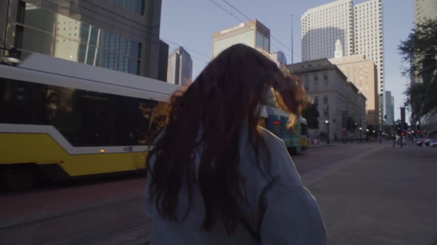 The woman walks past the bus in the city