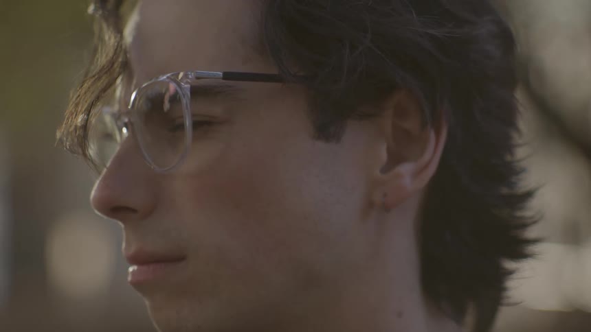 A mans head is shown with his eyes closed appearing to be thinking against a blurred background