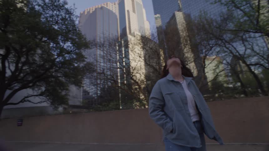 Young woman standing on a downtown street looking up at tall buildings and skyscrapers