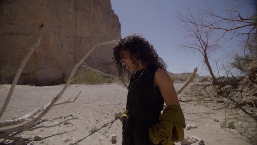The woman is thinking by the driftwood in the desert