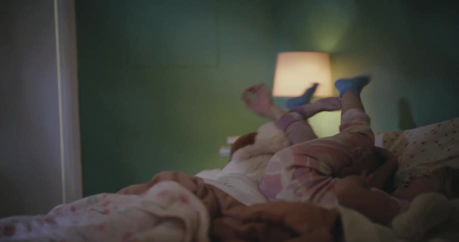 The girl rolls around playing in the bed