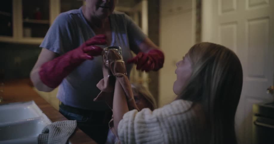 Adult woman and two young girls drying cups in a kitchen indoors