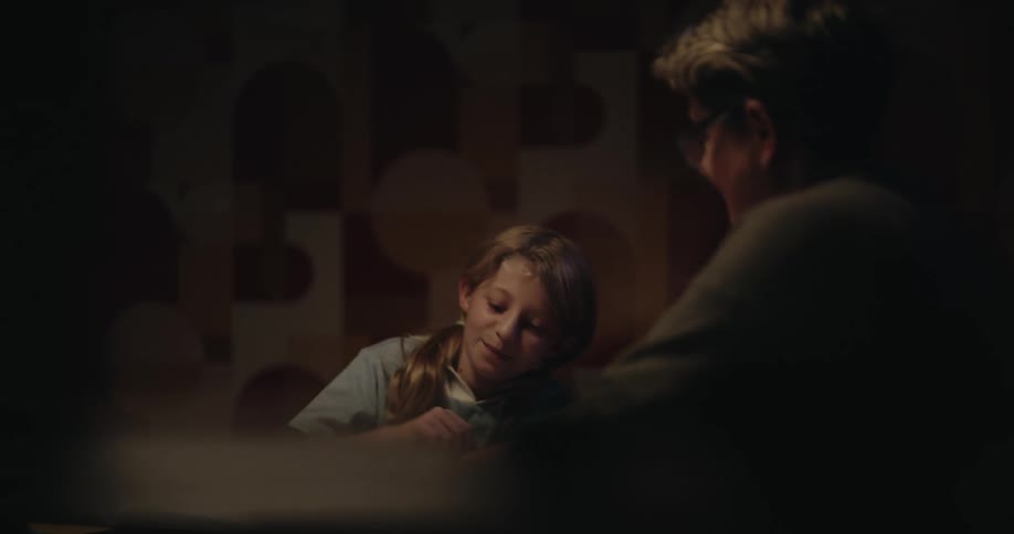 The mother hands her daughter a pencil to do homework