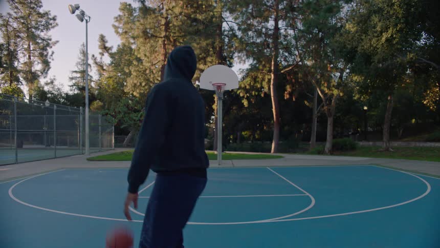 Young man dribbles the basketball on the court and throws it through the hoop