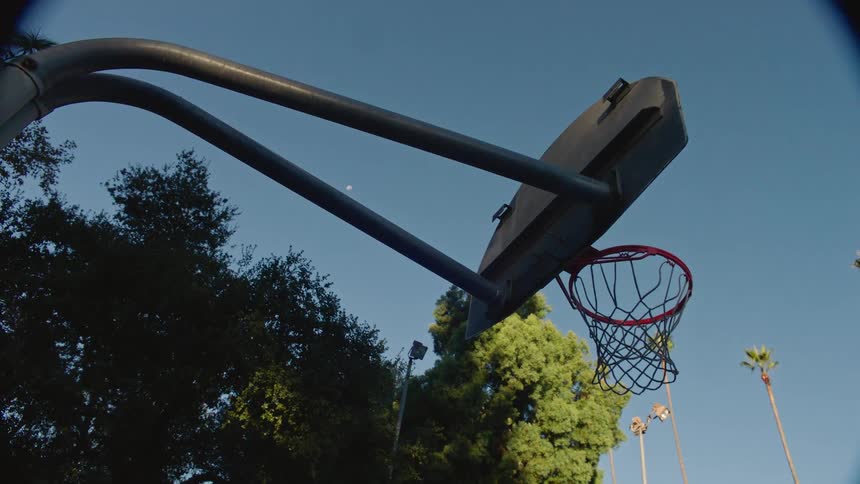 Basketball falling into the hoop on an outdoor court