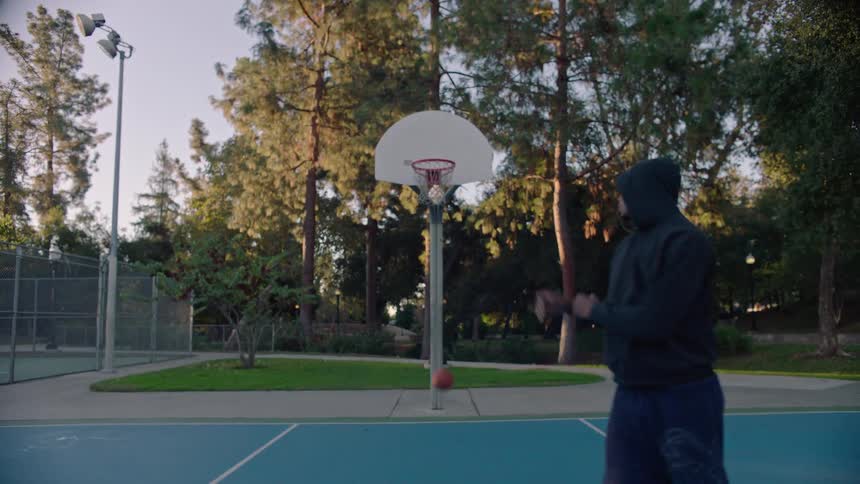 Young man stands on the basketball court and throws the ball through the hoop