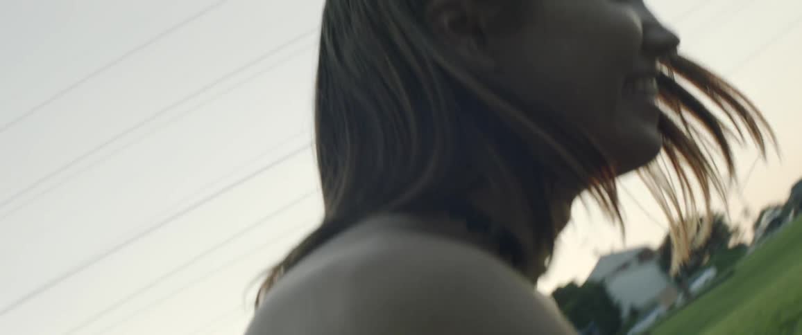 Girl tries to throw food into another girls mouth outside while sun sets
