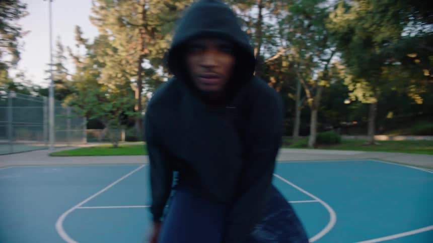 The man dribbles the basketball and sways back and forth