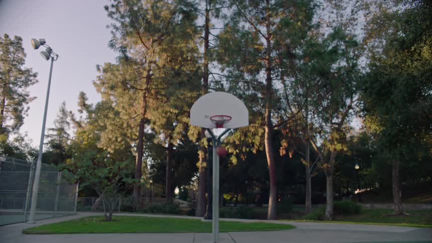 Ball flies across the basketball court hitting the backboard and falls through the hoop