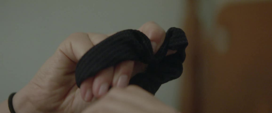 A woman laying down and playing with a hair scrunchie