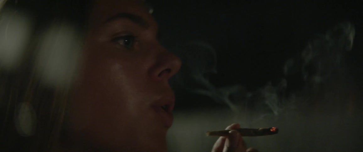 A woman sits outside smoking a joint