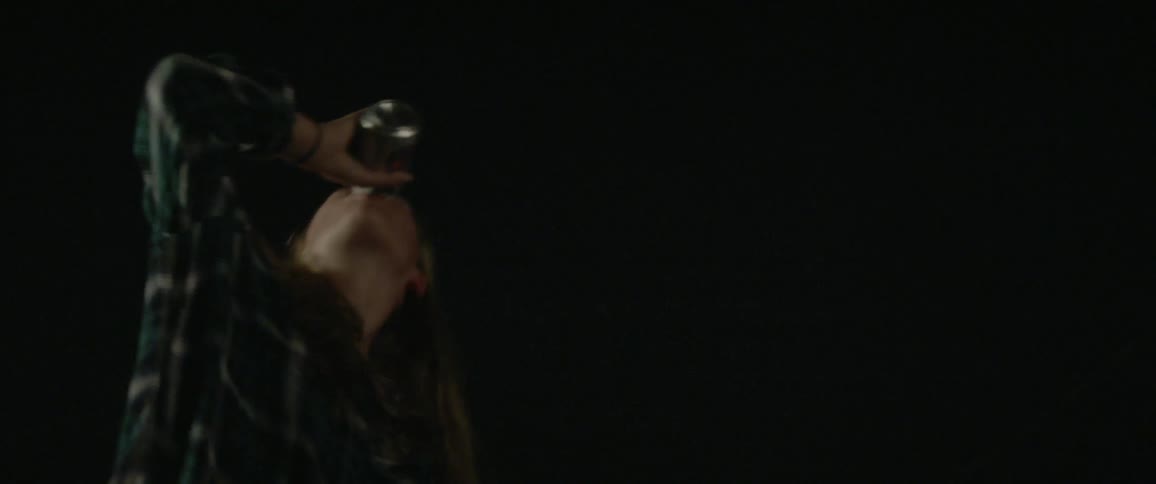 Woman drinking a can of beer outside in the dark night