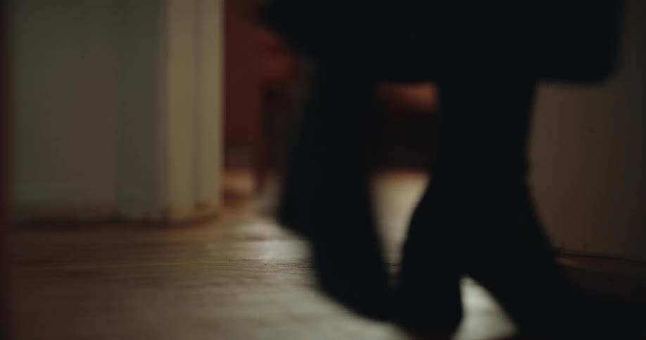Woman wearing boots walks past an open bedroom door
