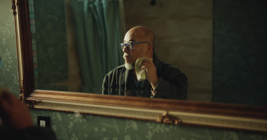 The man cleans his face in the mirror