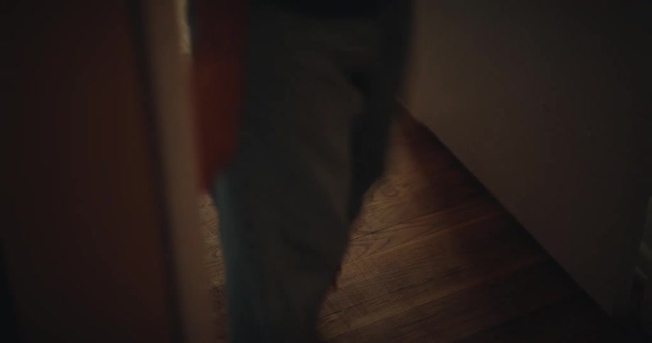 A close view shows the feet and lower legs of a group of children as they walk across a polished wood floor from one room into another