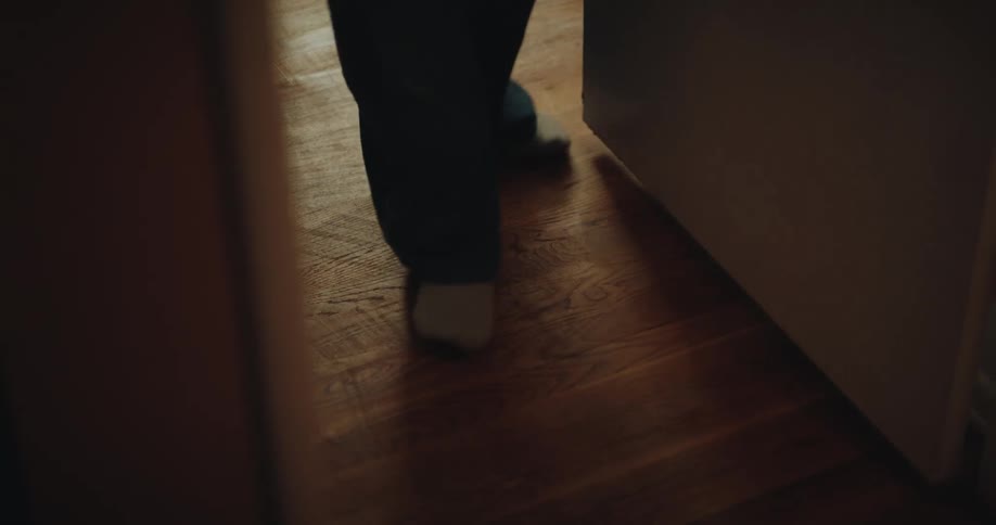 A person walking indoors past a couch in the sitting room