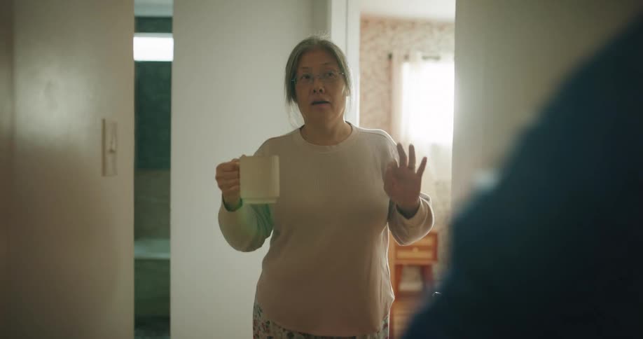 Elderly man and woman walk down an interior corridor gesturing with their hands