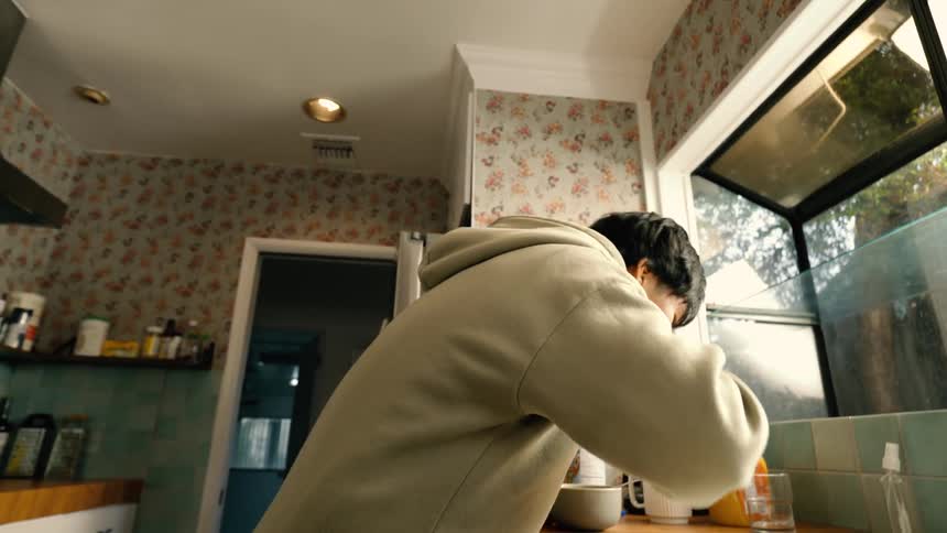 Teenager runs through the kitchen and grabs a piece of fruit