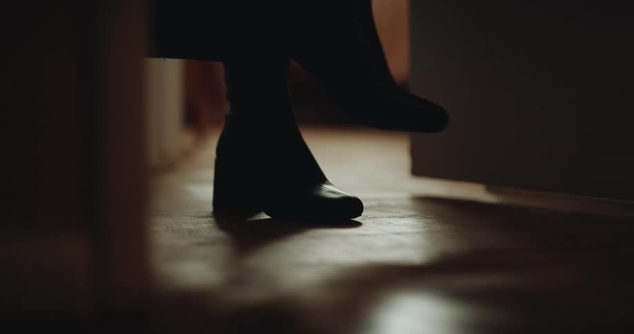 A woman in her living room putting on her shoe before heading out