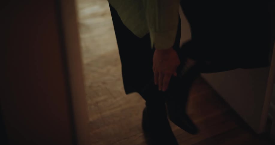 Person walking down a hallway and adjusting their boot