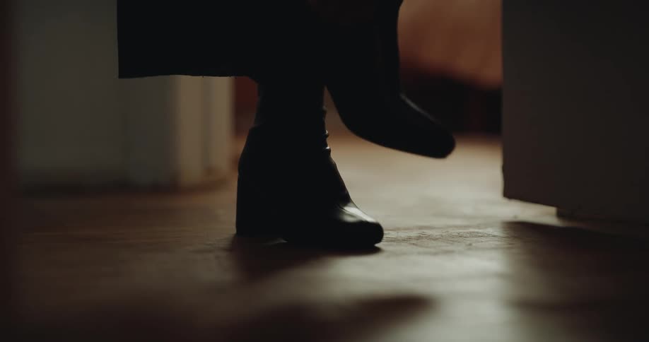 Person walks in heeled boots on wooden floor in warmly lit indoor setting