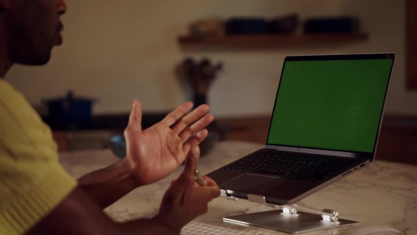Man sitting in a meeting facing a laptop at a table