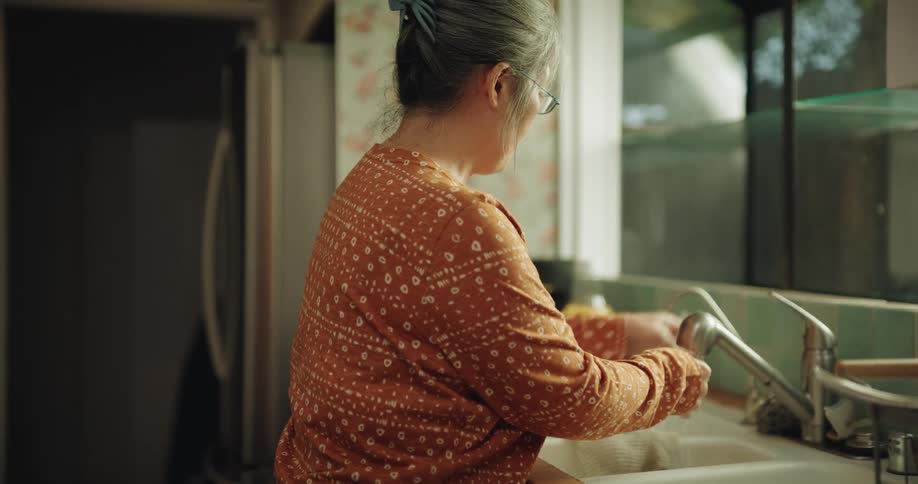 Asian mother cleaning up after breakfast preparation in the kitchen