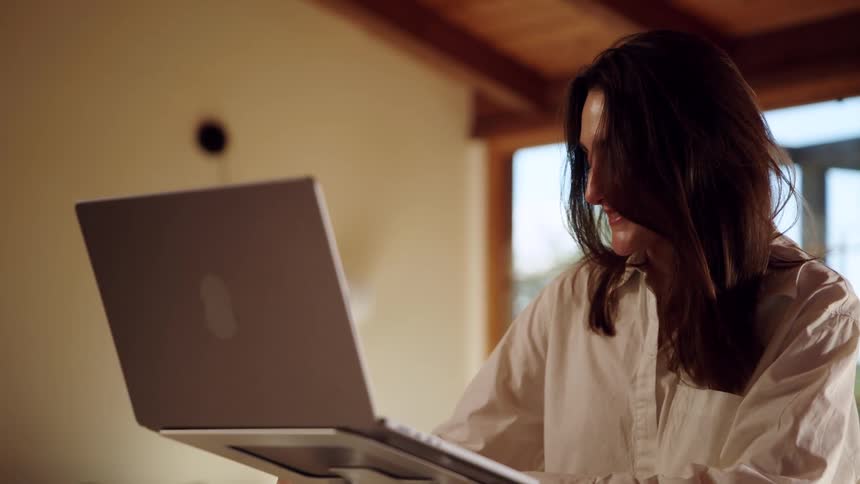 Person with long hair wears light shirt while engaging with laptop in welllit indoor setting