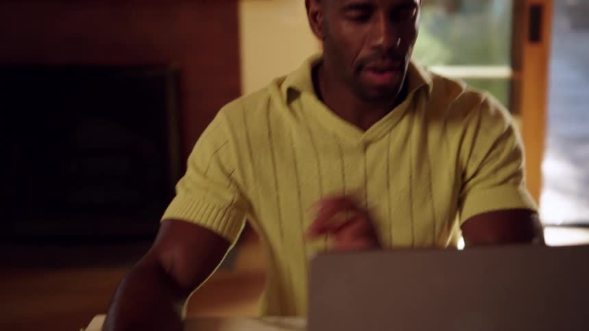 Person writes in spiral notebook beside laptop on marble table in indoor setting
