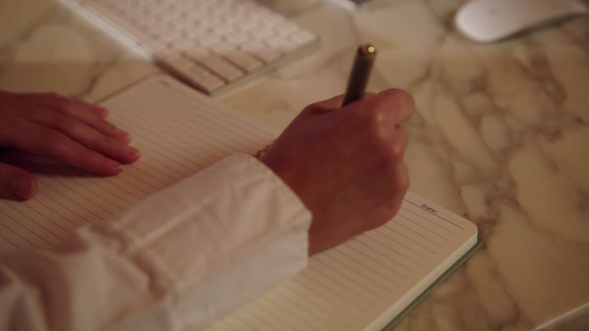 Adult hands type on a computer keyboard and write in a notebook