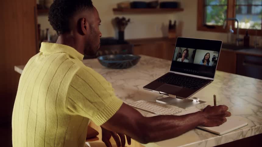 The man takes notes while on a video call