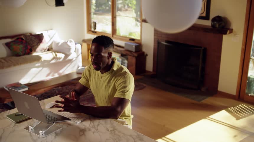 Person smiles during video call in welllit room with laptop on marble table