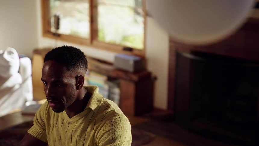Man talks while seated indoors with natural light coming through a window