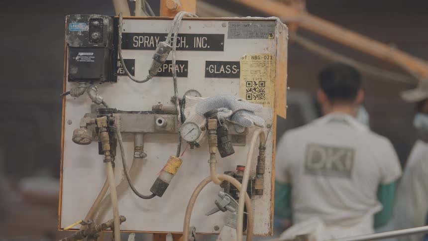 Industrial spray control panel with hoses valves and gauges with an operator working in the background