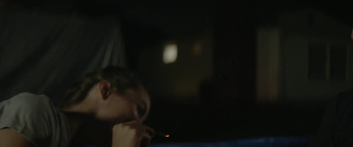 A woman laughing and holding a joint outside at night