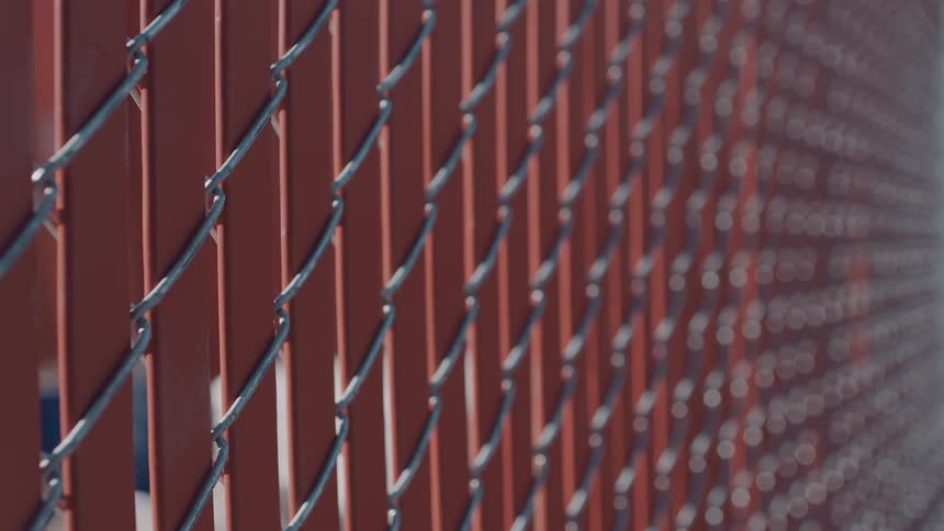 Chainlink fence with vertical red slats creates geometric pattern and visual depth