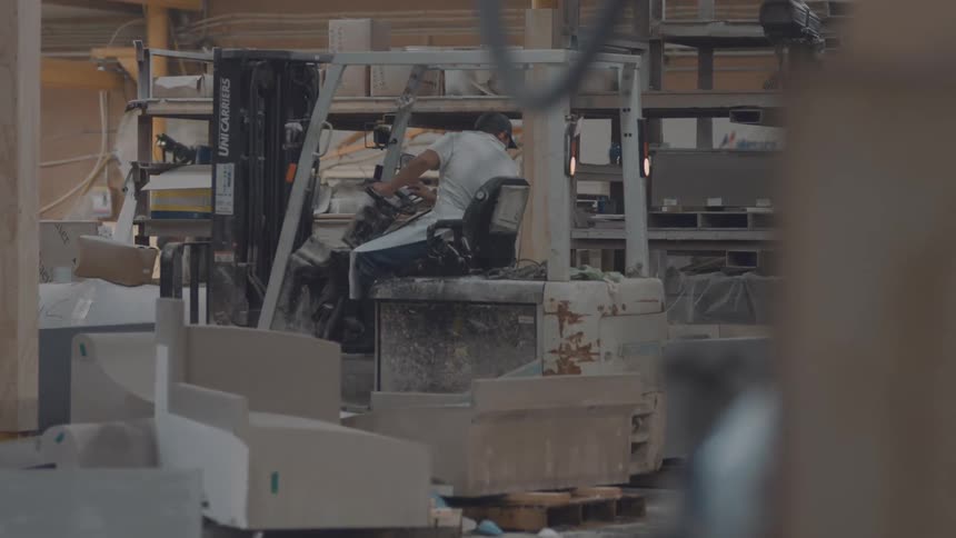 Operator drives a forklift in an industrial area surrounded by blocks and structures