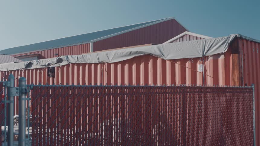 Shipping containers are lined up behind a metal fence in an industrial area