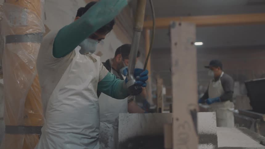 Worker wears protective equipment while operating an industrial tool in a factory setting