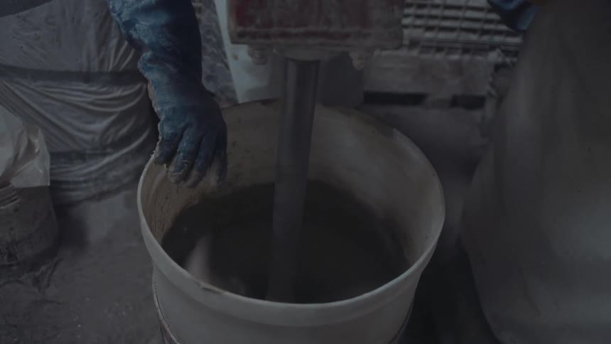 A construction worker mixing cement in a bucket