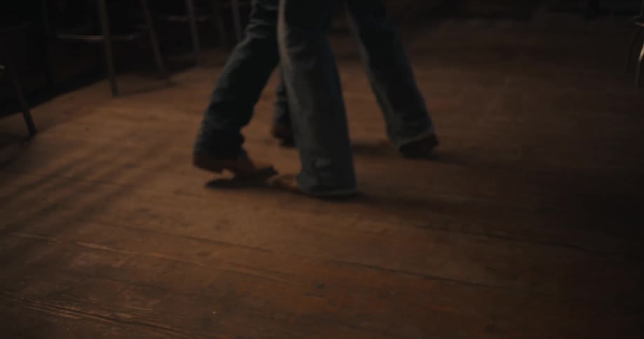 Couple dances closely in a bar with low lighting and rustic decor