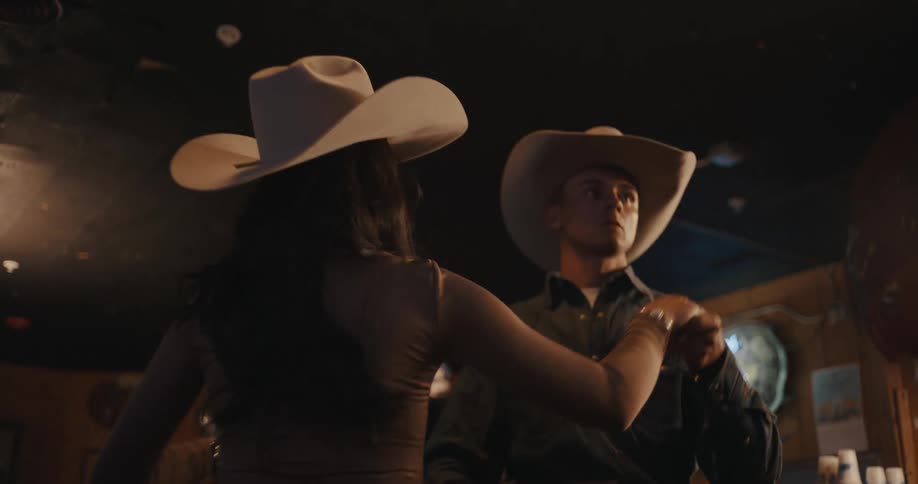Person dances while holding a partner in a dimly lit indoor space with rustic decor