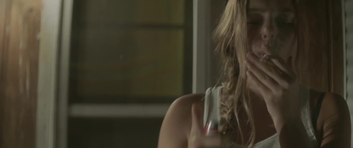 Woman smokes a cigarette outside at night
