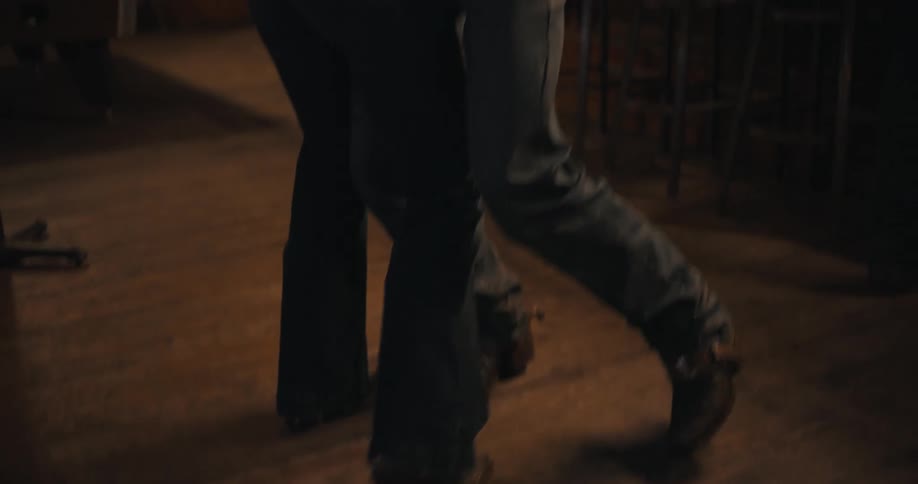 Couple dancing in a westernstyle bar wearing cowboy hats under low lighting