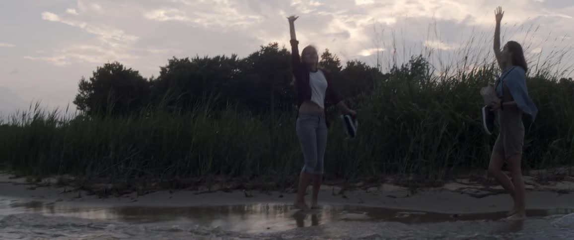 Women walk barefoot on a beach
