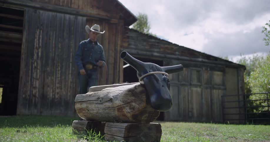 The man swings his lasso at the bull statue